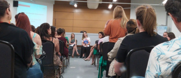 Mulheres em cadeiras ouvindo uma palestra