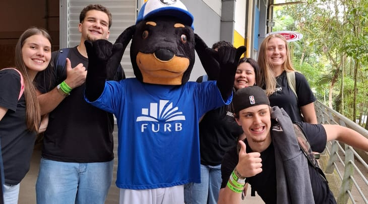 Foto com estudantes ao redor do mascote Interacão FURB
