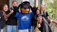 Foto com estudantes ao redor do mascote Interacão FURB